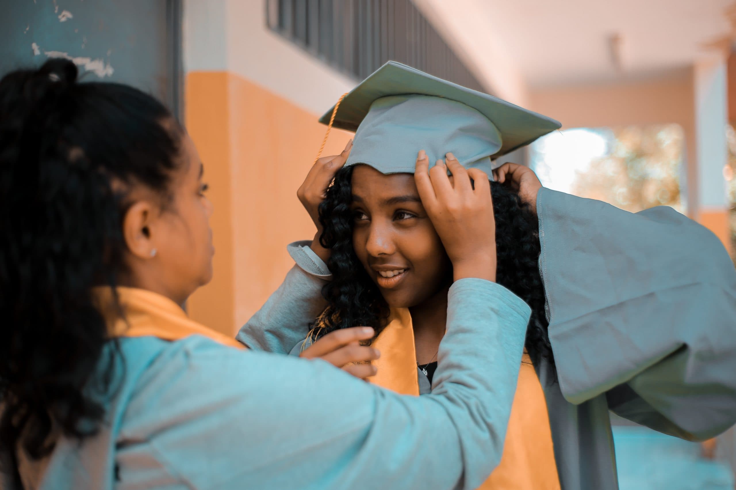 two girls adjusting graduation cap who will soon be part of a company's campus hiring strategy